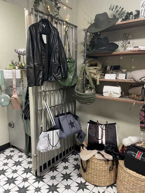 Clothing and accessories displayed in a stylish boutique with hats, bags, and leather jackets.