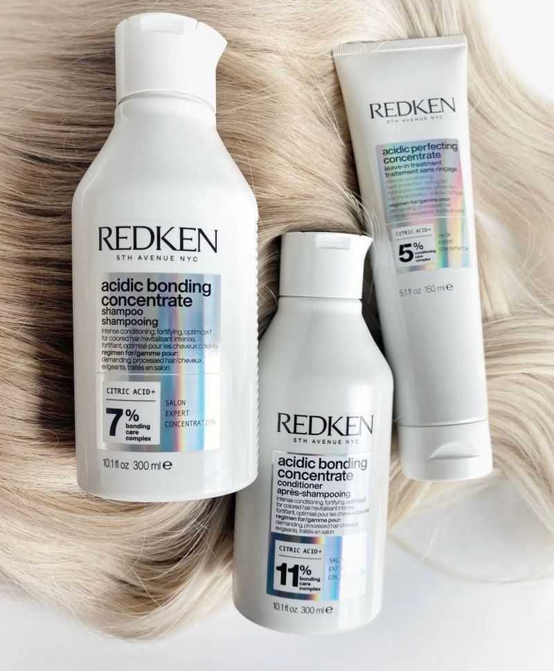 Redken acidic hair care trio on blonde hair background.